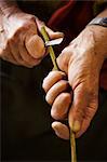 Close up of woman cutting a piece of willow in a basket weaver's workshop.