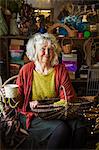 Woman sitting in a basket weaver's workshop, holding a basket.