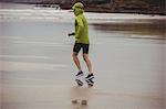 Rear view of athlete running on the beach