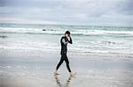 Athlete in wet suit wearing swimming goggles while walking on the beach