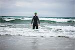 Athlete in wet suit standing in the sea on beach