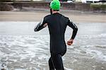 Rear view of athlete running towards the beach