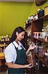 Female shopkeeper holding a jar of spice in shop