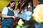 Female shopkeeper holding a jar of spice in shop