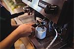 Close-up of waitress taking coffee from espresso machine in cafeteria