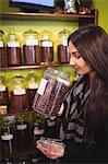 Beautiful woman smelling jar of coffee beans in shop
