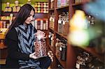 Beautiful woman holding a jar of spice in shop
