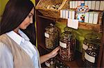 Beautiful woman looking at jar of spice in shop