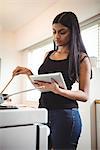 Woman cooking and using digital tablet in kitchen