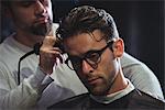 Man getting his hair trimmed with trimmer in barber shop