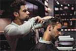 Hairdresser combing clients hair in barber shop