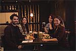 Portrait of happy friends enjoying food together in bar