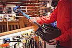 Close-up of man selecting shovel in a shop