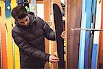 Handsome man selecting ski in a shop