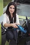 Portrait of beautiful woman charging electric car on street
