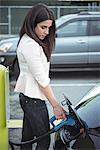 Beautiful woman charging electric car on street