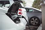 Close-up of car being charged with electric car charger at charging station