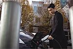 Confident man charging electric car at electric vehicle charging station