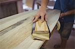 Close-up of man using sanding box on surfboard in workshop