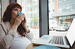 Pregnant businesswoman having coffee in office cafeteria