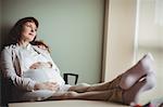 Pregnant businesswoman relaxing with her feet up in office