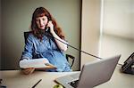 Pregnant businesswoman talking on telephone while working in office