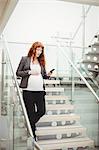 Pregnant businesswoman walking down stairs in office