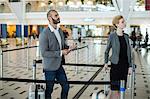 Businesspeople waiting in queue at the check-in counter with luggage in airport terminal