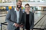 Portrait of smiling businesspeople with passport waiting in queue at airport terminal