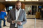 Businessman using digital tablet in waiting area at airport terminal