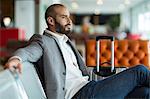 Thoughtful businessman sitting on chair in waiting area at the airport terminal
