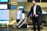 Businessman picking his luggage from baggage claim area at airport terminal