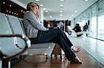 Businesswoman sleeping on chair in waiting area at airport terminal