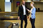 Smiling couple interacting with each other in waiting area at airport terminal