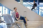 Smiling woman talking on mobile phone in waiting area at airport terminal