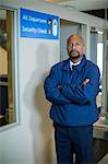 Portrait of airport security officer standing with arms crossed in airport terminal