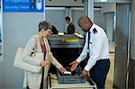 Airport security officer checking commuter mobile phone in airport terminal
