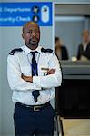 Portrait of airport security officer standing with arms crossed in airport terminal