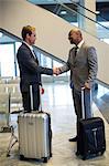 Business people shaking hand in waiting area with airport