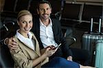 Portrait of happy couple using mobile phone at airport