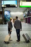 Rear view of businesspeople with luggage at airport terminal