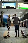 Low section of businesspeople walking with luggage at airport terminal