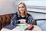 Woman smiling portrait of happy lovely and beautiful woman in casual clothes indoor sitting in cafe with tablet