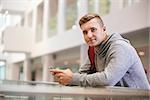 Young adult male student looks to camera in university lobby