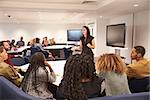 Female teacher addressing university students in a classroom
