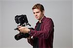 Studio Portrait Of Male Videographer With Film Camera