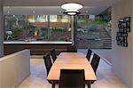 Dining room at twilight overlooking garden with open bi-fold glass doors. An open plan home.