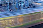 Commuter trains swing around the tracks curving into Ueno Station in Tokyo, Japan in this telephoto view using a slow shutter speed that creates the blurring motion of the passing trains.