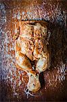 Entire roast chicken on a cutting board (top view)