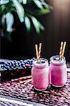 Berry smoothies in two screw-top jars with straws